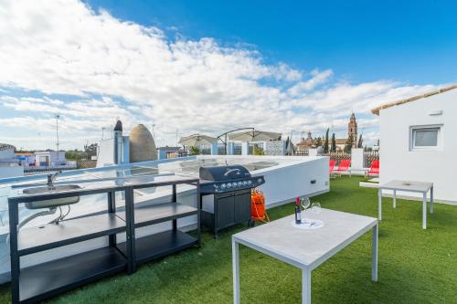 a outdoor entertaining area with a grill and tables on a roof at CASA DE LA SEÑORA in Palma del Río