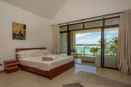 een slaapkamer met een bed en uitzicht op de oceaan bij Villa 4 chambres THE BAY, pieds dans l'eau au centre de Grand Baie in Grand Baie