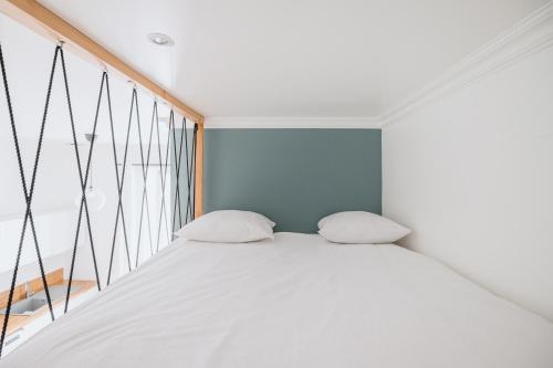 un lit blanc dans une chambre avec une fenêtre dans l'établissement Studio Fêtes napoléoniennes Villa Marie Celine, à Vichy