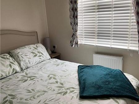 un letto con una coperta blu sopra in una camera da letto di The willerby whitetower Caernarfon a Llanwnda