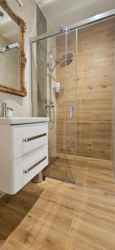 a bathroom with a shower with a sink and a mirror at Apartamenty w Sercu Sosnówki in Sosnówka