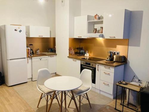 une cuisine avec une table et des chaises et un réfrigérateur blanc dans l'établissement Appartement avec terrasse, Arena Paris sud 7 km, à Clamart