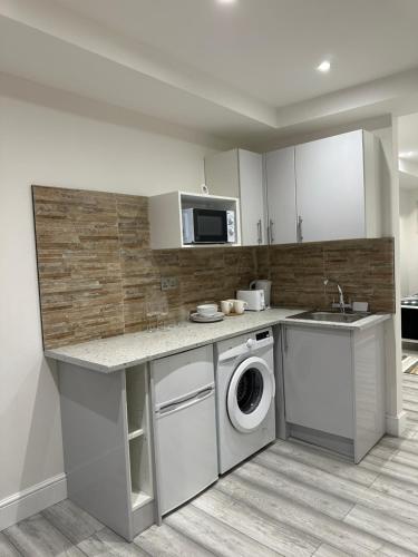 a kitchen with a washing machine and a sink at Guest&rest Ealing 6 in Ealing