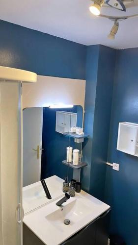 La salle de bains est pourvue d'un lavabo blanc et d'un mur bleu. dans l'établissement Hibiscus : T2 Melun, à Melun
