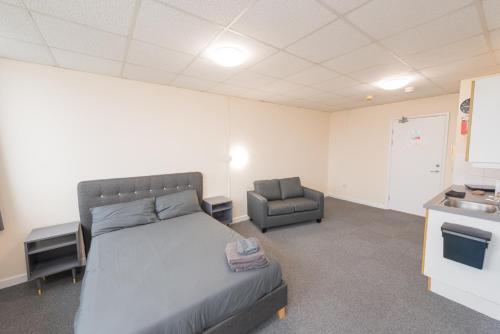 um quarto com uma cama e uma cadeira em Superior En-suite Apartment 6 em Plymouth