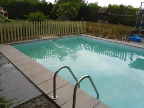 a swimming pool in a yard with a wooden fence at la mini ferme de maëlou in Sermaises