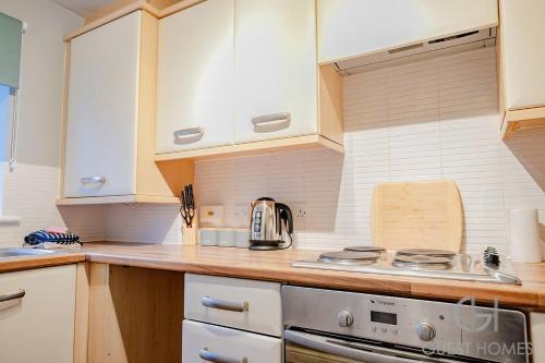 a kitchen with white cabinets and a stove at Blackthorn in Bury Saint Edmunds