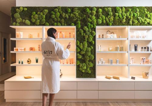 a woman standing in front of a green wall at 6717 Nature Hôtel & Spa Le Clos des Délices in Ottrott