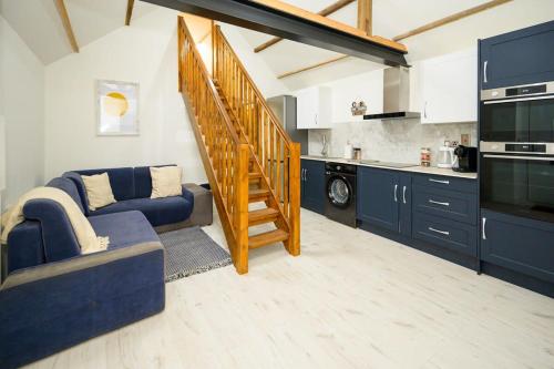 a living room with a blue couch and a kitchen at The Den by StayStaycations in Rugeley