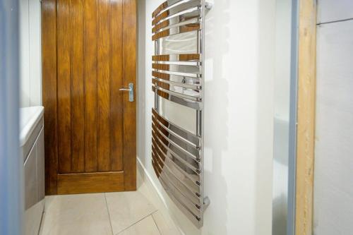 a towel rack in a bathroom with a wooden door at The Den by StayStaycations in Rugeley