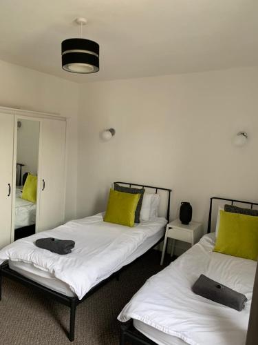 Duas camas num quarto com almofadas amarelas em Dunhill Townhouse em Goole