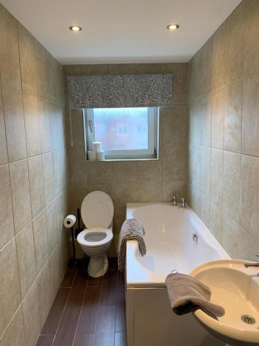 a bathroom with a tub and a toilet and a sink at Dunhill Townhouse in Goole