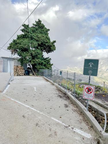 a road with a fence and a no parking sign at Mountain Bliss Guesthouse 2 next to Sougia in Agrilés