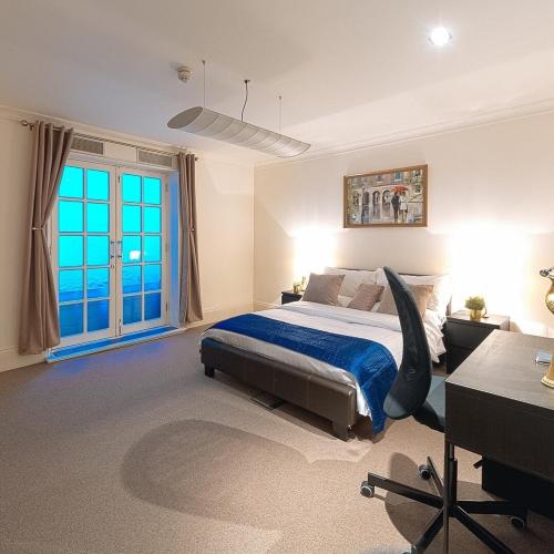 Curzon Residences في لندن: غرفة نوم بسرير ومكتب ونافذة