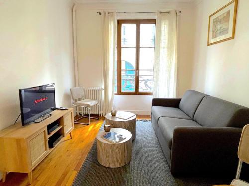 un salon avec un canapé et une télévision dans l'établissement L' Appartement Richard-Lenoir, à Paris
