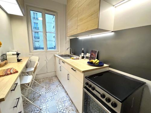 une cuisine avec un évier et une cuisinière dans l'établissement L' Appartement Richard-Lenoir, à Paris