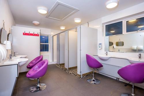 W łazience znajdują się fioletowe krzesła, umywalki i lustra. w obiekcie Podumna Glamping Village w mieście Portumna