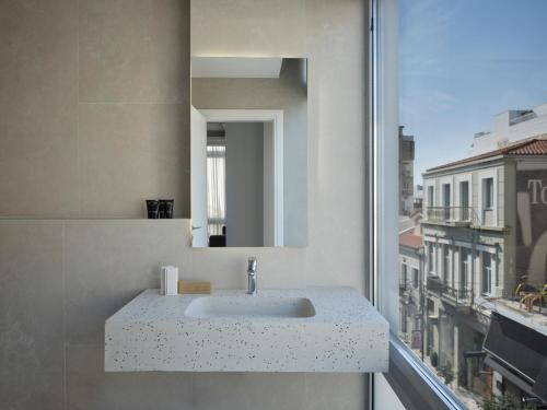 a bathroom sink with a mirror and a window at RESIDENCE PATRAS in Patra