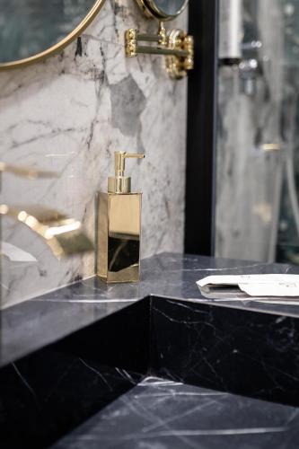 a gold soap dispenser on a black counter in a bathroom at Maison 31 -Luxury Apartments in Santa Marinella