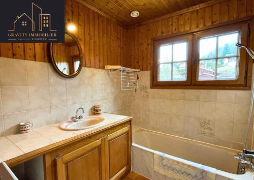 La salle de bains est pourvue d'un lavabo, d'une baignoire et d'un miroir. dans l'établissement Chalet 4 pièces + Mezzanine , Les Carroz, aux Carroz d'Arâches