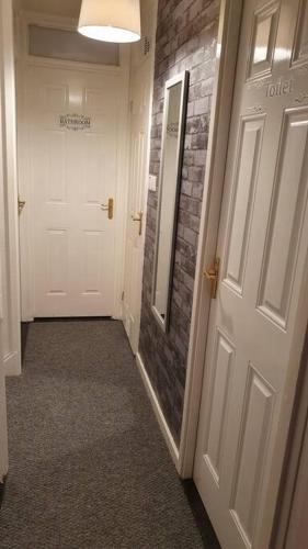 a hallway with a white door and a brick wall at Airport,NEC,JLR,Bham. Entire house 5 beds. in Kingshurst