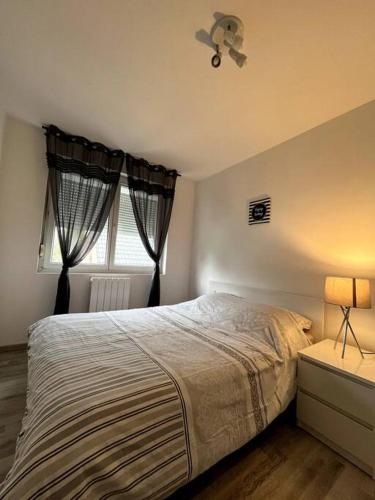 um quarto com uma cama grande e uma janela em Le coin cosy 38 m2 em Orchies