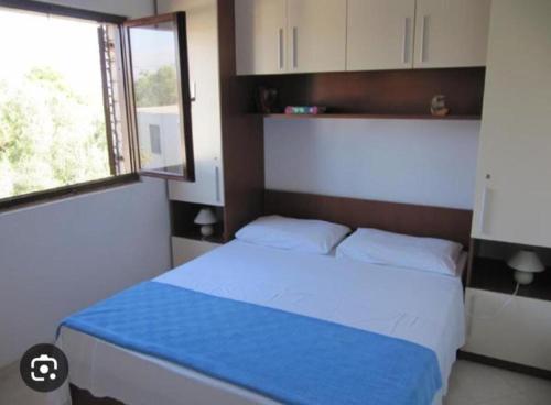 a bedroom with a bed with a blue blanket and a window at Hetenika in Sućuraj