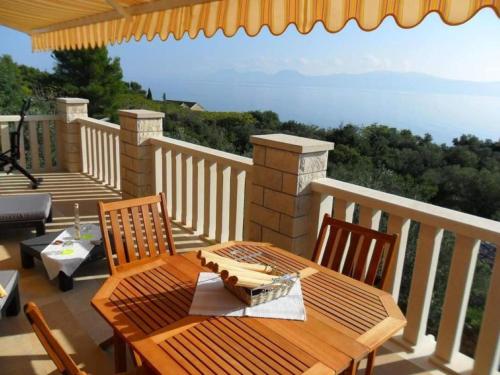 a wooden table and chairs on a balcony at Hetenika in Sućuraj