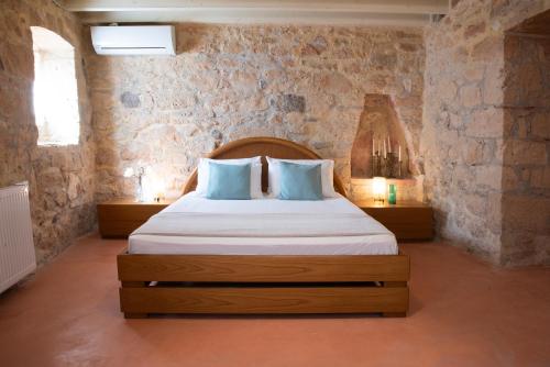 a bedroom with a bed in a stone wall at Traditional town house in Egina