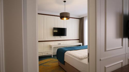 a small bedroom with a bed and a television at Grand Hotel Belushi in Boge