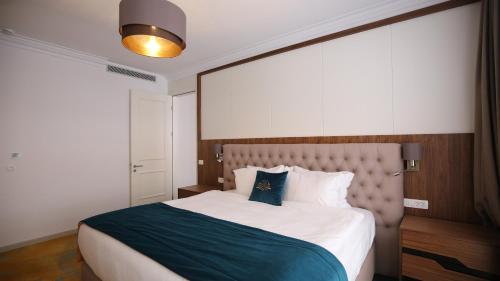 a bedroom with a large bed with a blue pillow at Grand Hotel Belushi in Boge