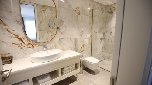 a bathroom with a sink and a mirror and a toilet at Grand Hotel Belushi in Boge