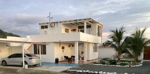 une maison blanche avec une voiture garée devant elle dans l'établissement Villa Comando Privacidad Cerca al Mar, à Briseño