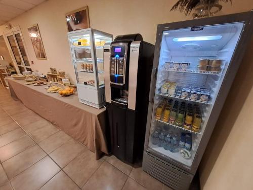 a refrigerator full of drinks and a table in a room at Hotel Anjou à L'Océane Angers-Le Mans in Saint-Sylvain-dʼAnjou