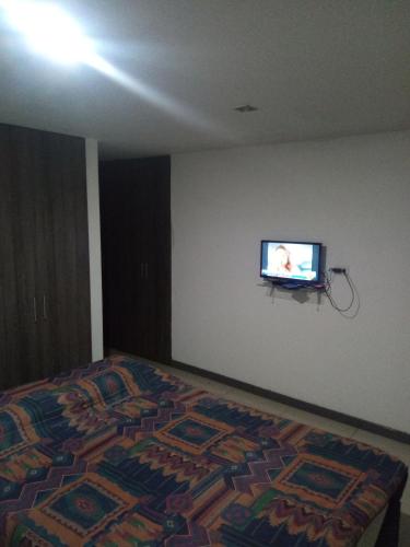 ein Schlafzimmer mit einem Bett und einem TV an der Wand in der Unterkunft Altea in Popayan