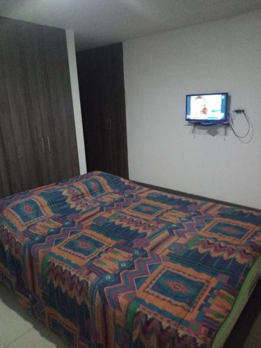 ein Bett mit einer bunten Decke und einem TV an der Wand in der Unterkunft Altea in Popayan