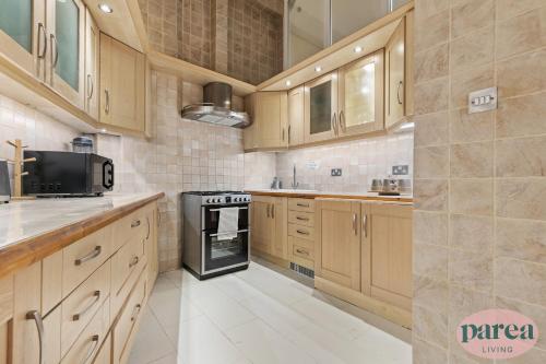 cocina grande con armarios de madera y fogones en Parea Living - Canary Wharf, Secluded Luxury Flat w Free Parking & Remote Working en Londres