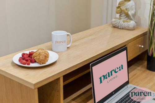 una mesa con un ordenador portátil y un plato de comida en Parea Living - Canary Wharf, Secluded Luxury Flat w Free Parking & Remote Working en Londres