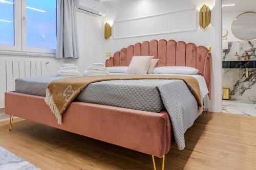 a large bed with a pink headboard in a room at Maison 31 -Luxury Apartments in Santa Marinella