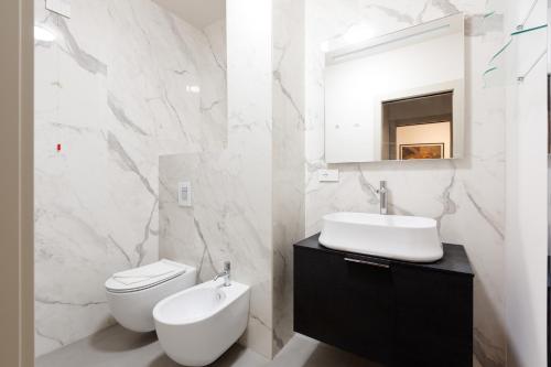 a white bathroom with a sink and a toilet at GuestHost - Cordusio Enchanting Apartment in Milan