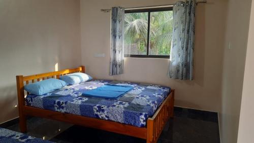a bedroom with a bed with a blue comforter and a window at Samruddi Homestay in Kalasa