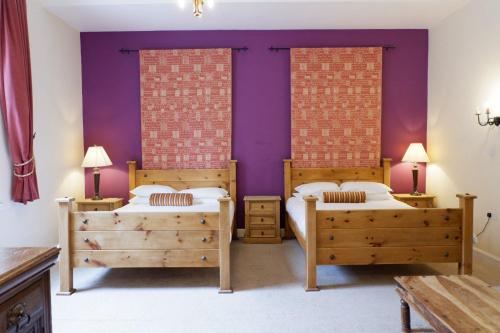 2 Betten in einem Zimmer mit lila Wänden in der Unterkunft Broomhall Castle Hotel in Stirling
