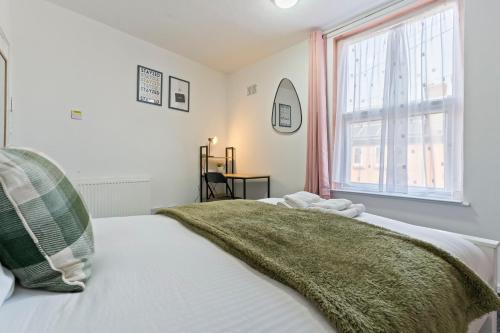 a bedroom with a bed with a green blanket on it at STAYZED N - NG7 Cosy Home, Free WiFi, Parking, Smart TV, Next To Nottingham City Centre, Ideal for Long Stays, Lots of Amenities in Nottingham