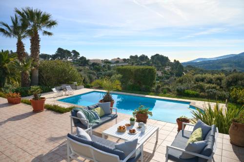 un patio avec une table et des chaises à côté d'une piscine dans l'établissement Sunlight Properties - Villa Belvédère, à Peymeinade