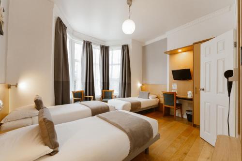 Una habitación de hotel con tres camas y un escritorio. en Star Hotel, en Londres