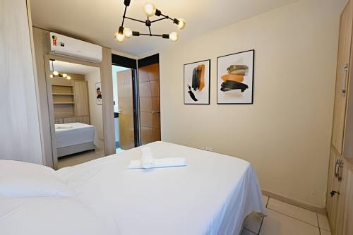 a bedroom with a white bed and a mirror at ESPETACULAR 1 dorm com piscina em Manaíra! in Tambaú