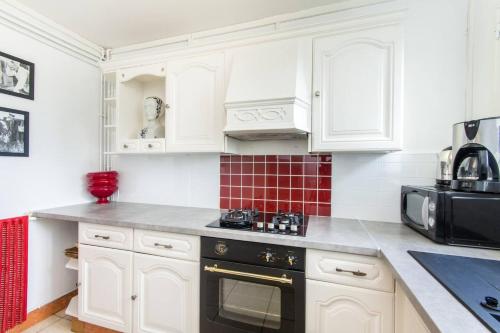 une cuisine avec des armoires blanches et un appareil noir dans l'établissement Appartement charmant au cœur de Caen - 70 m² - Parking inclus, à Caen