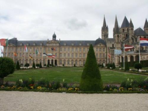 un grand bâtiment avec un parc en face dans l'établissement Appartement charmant au cœur de Caen - 70 m² - Parking inclus, à Caen