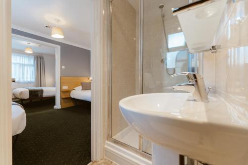 a bathroom with a sink and a shower and a bedroom at Star Hotel in London