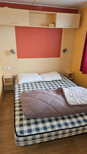 - un grand lit dans une chambre dotée d'un mur rouge dans l'établissement Mobilhome 573 camping 4* La Réserve 2 chambres, à Gastes